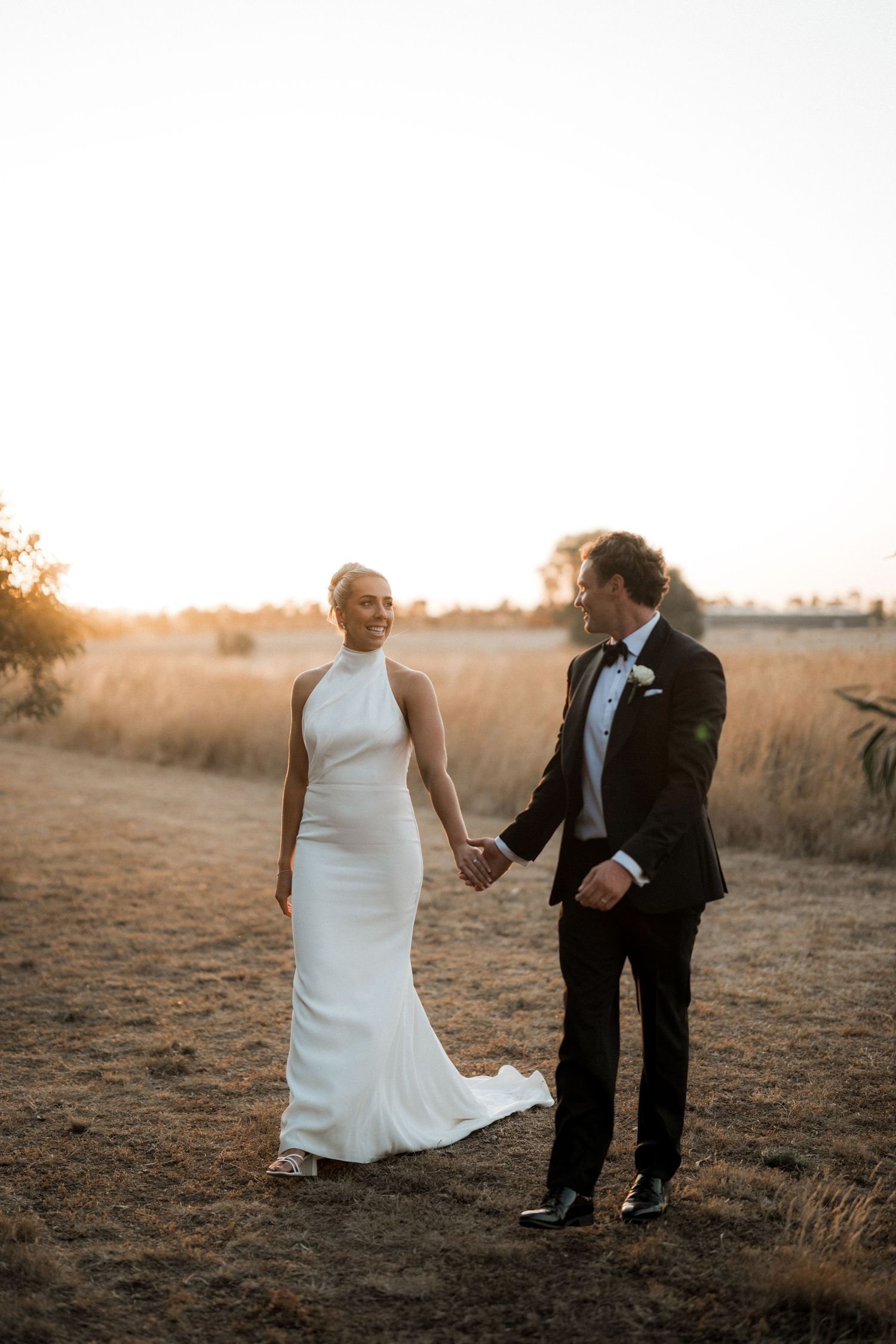A couple shares an intimate moment in a sun-drenched field during their wedding photoshoot.