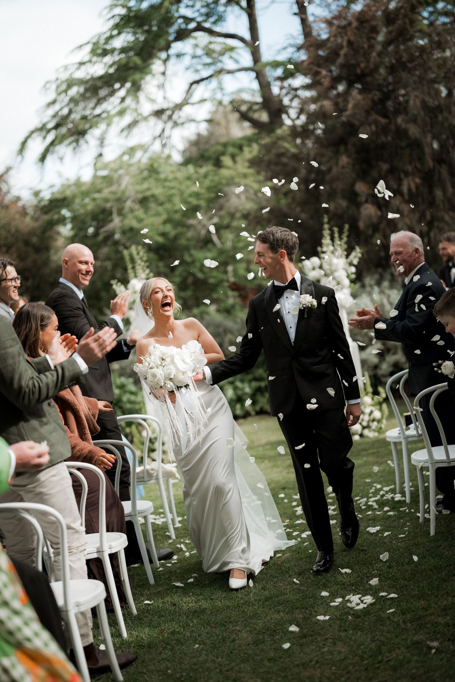 Wedding guests tossing confetti during an outdoor garden ceremony celebration.