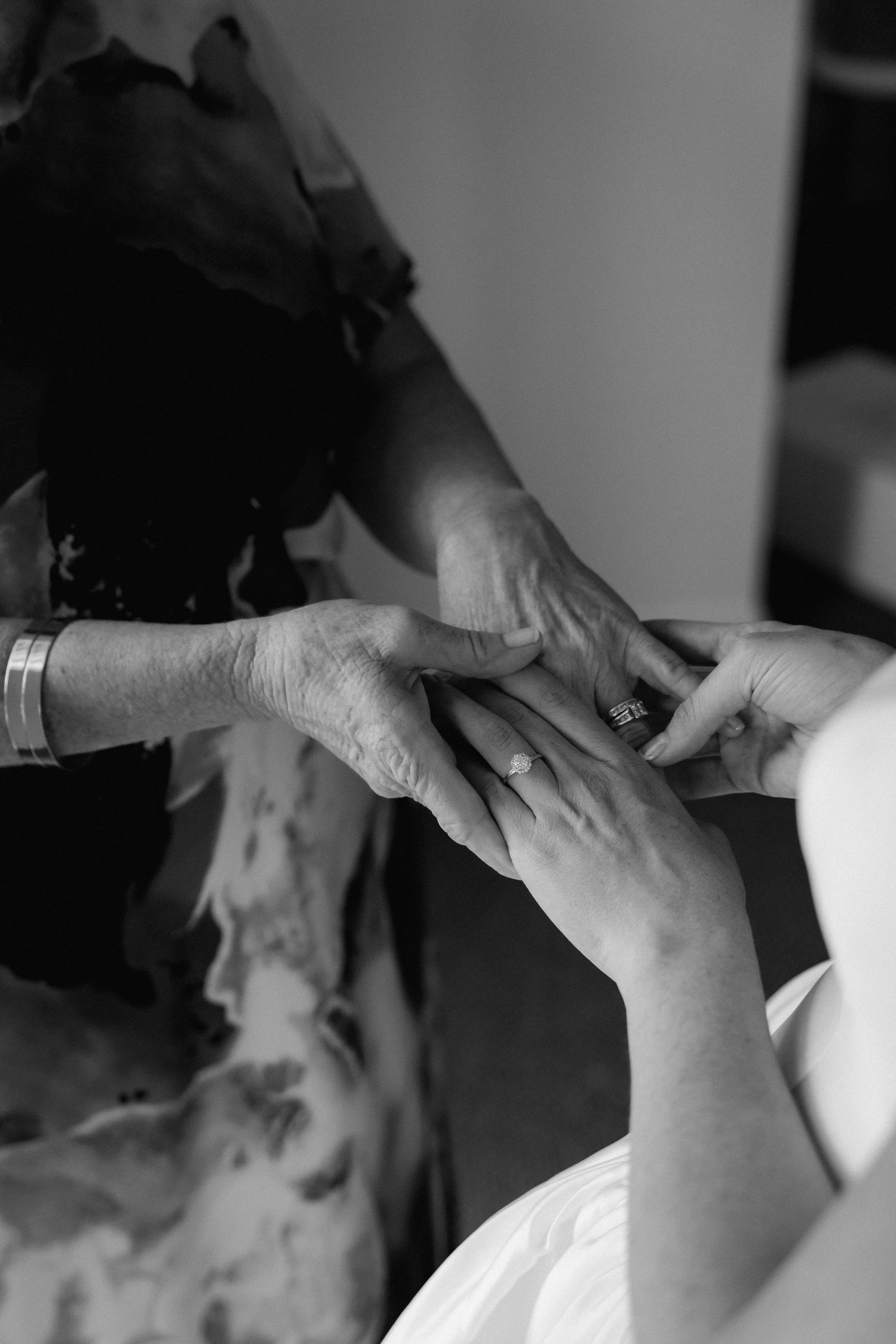 Close-up black and white photo of hands being held together in an intimate moment.