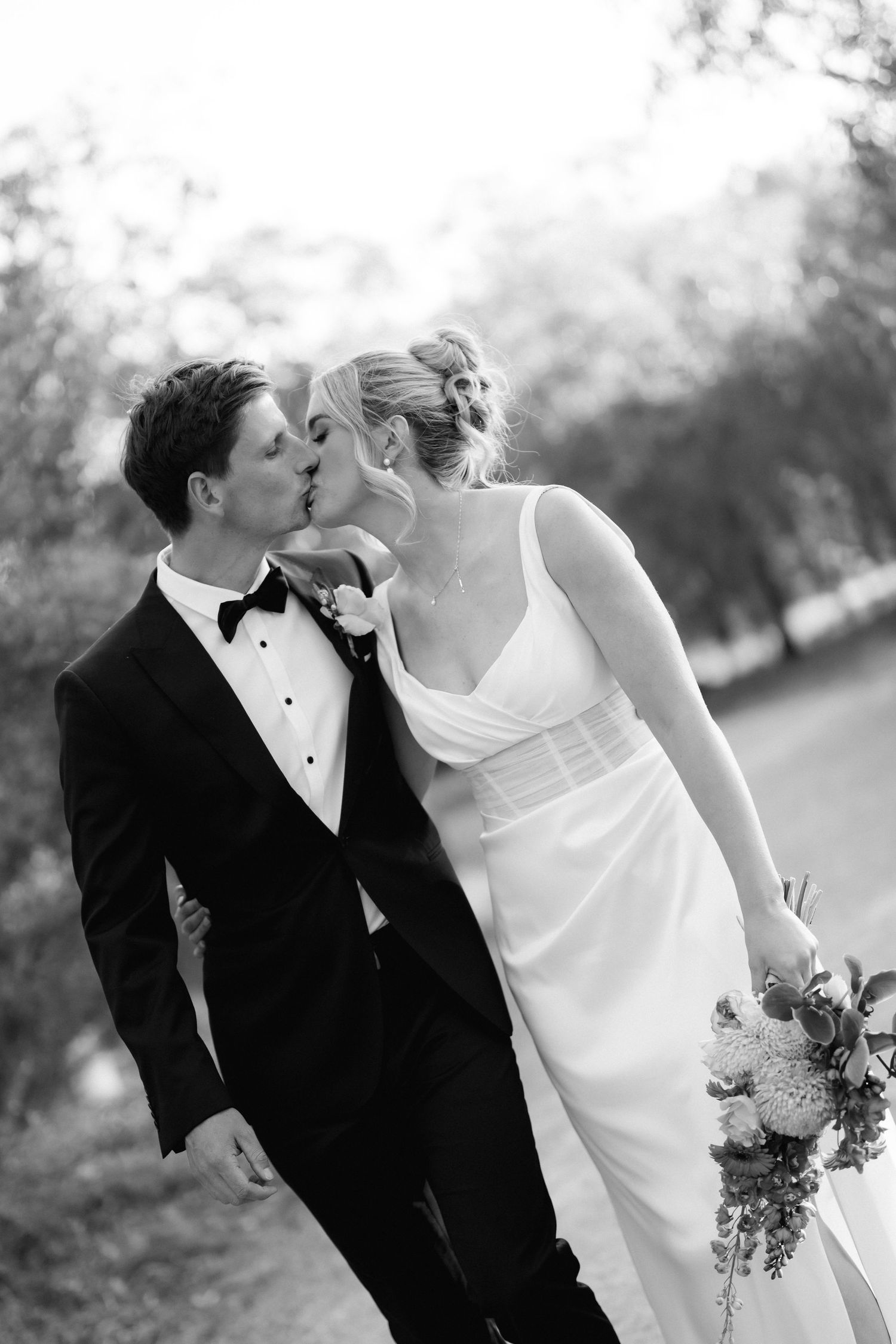 A romantic black and white wedding portrait of a couple sharing an intimate moment in an outdoor setting.