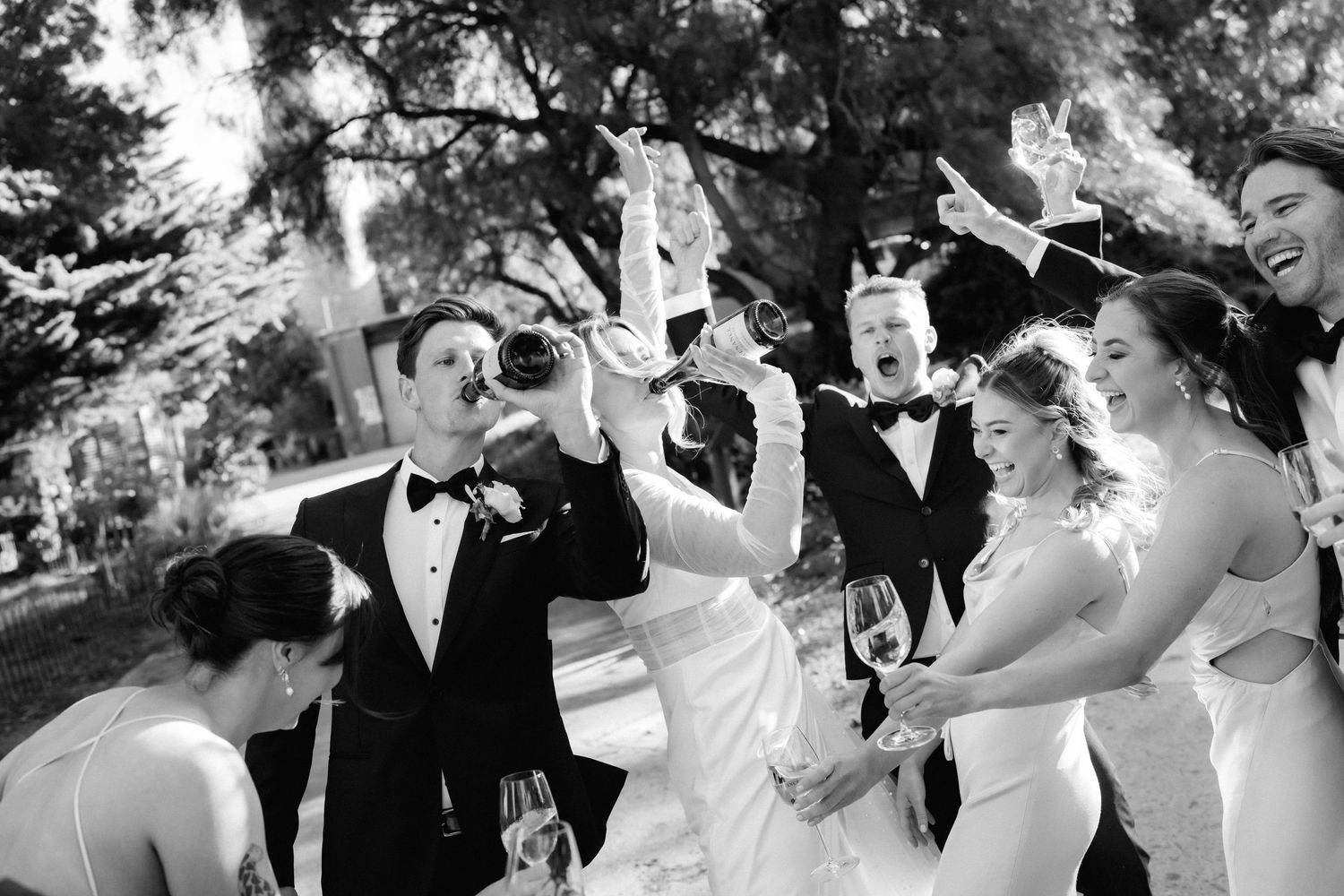 Wedding party toasting and celebrating with drinks in black and white photography.