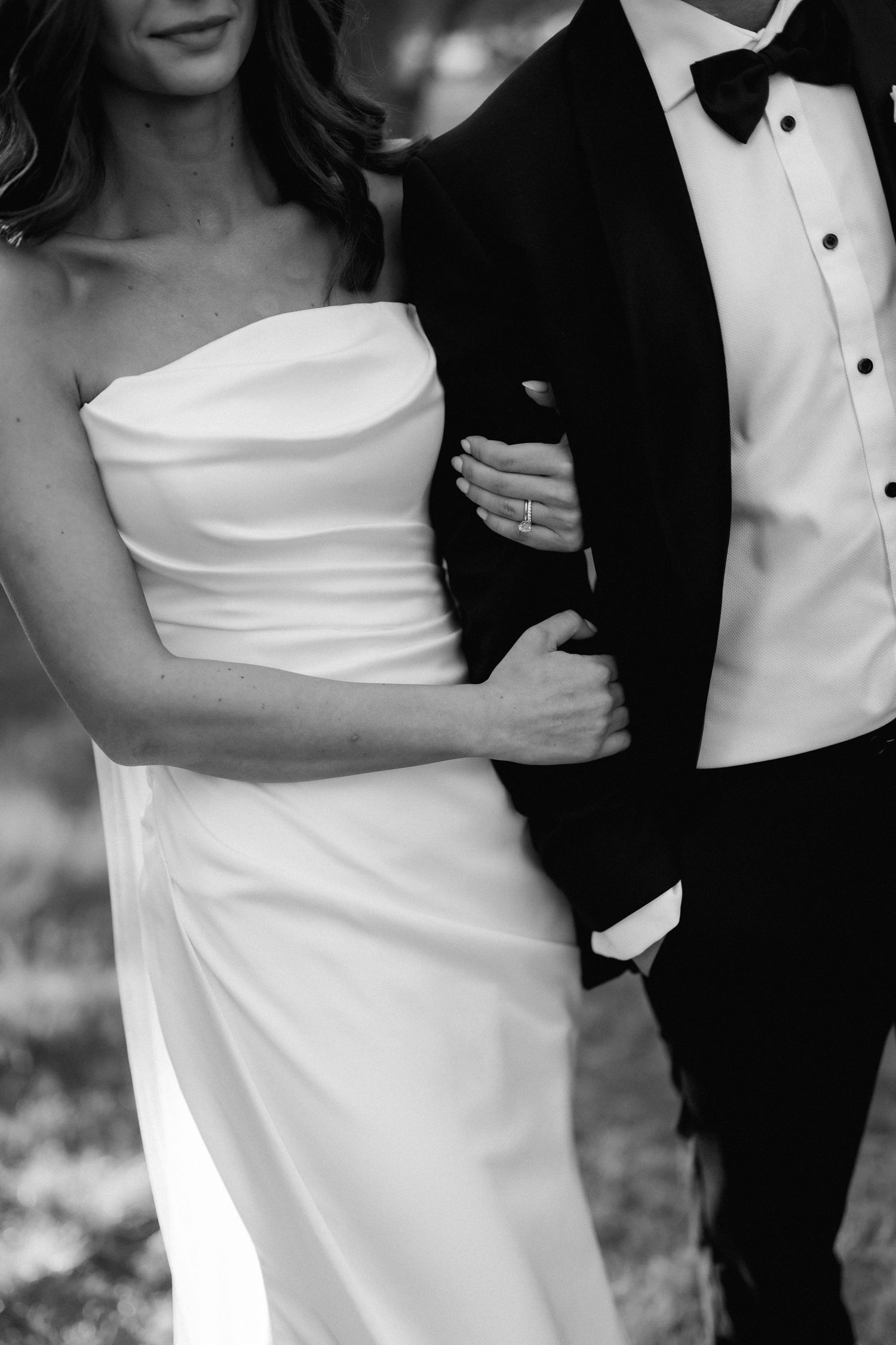 Close-up details of elegant white wedding dress and black tuxedo during formal portraits.