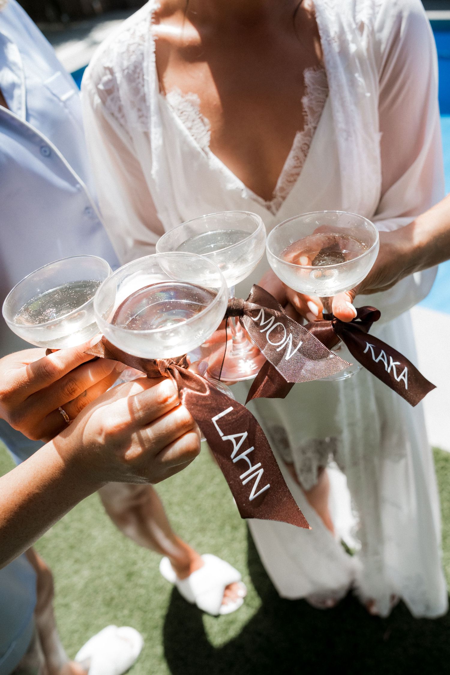 Wedding detail shots show hands holding delicate ribbons with text in an outdoor setting.