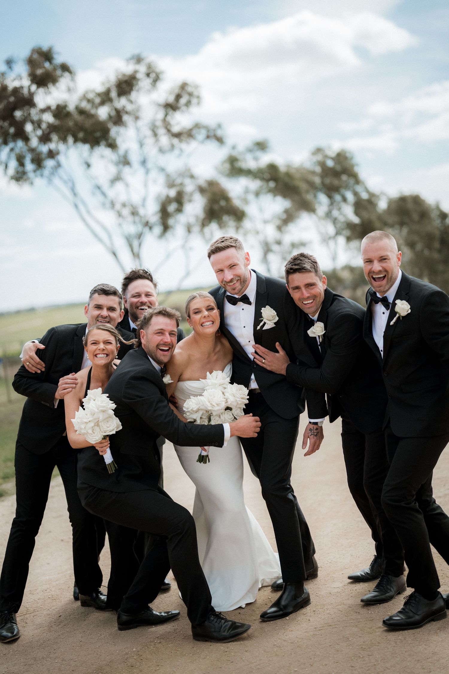 Wedding party creates fun poses on outdoor path during photo session.