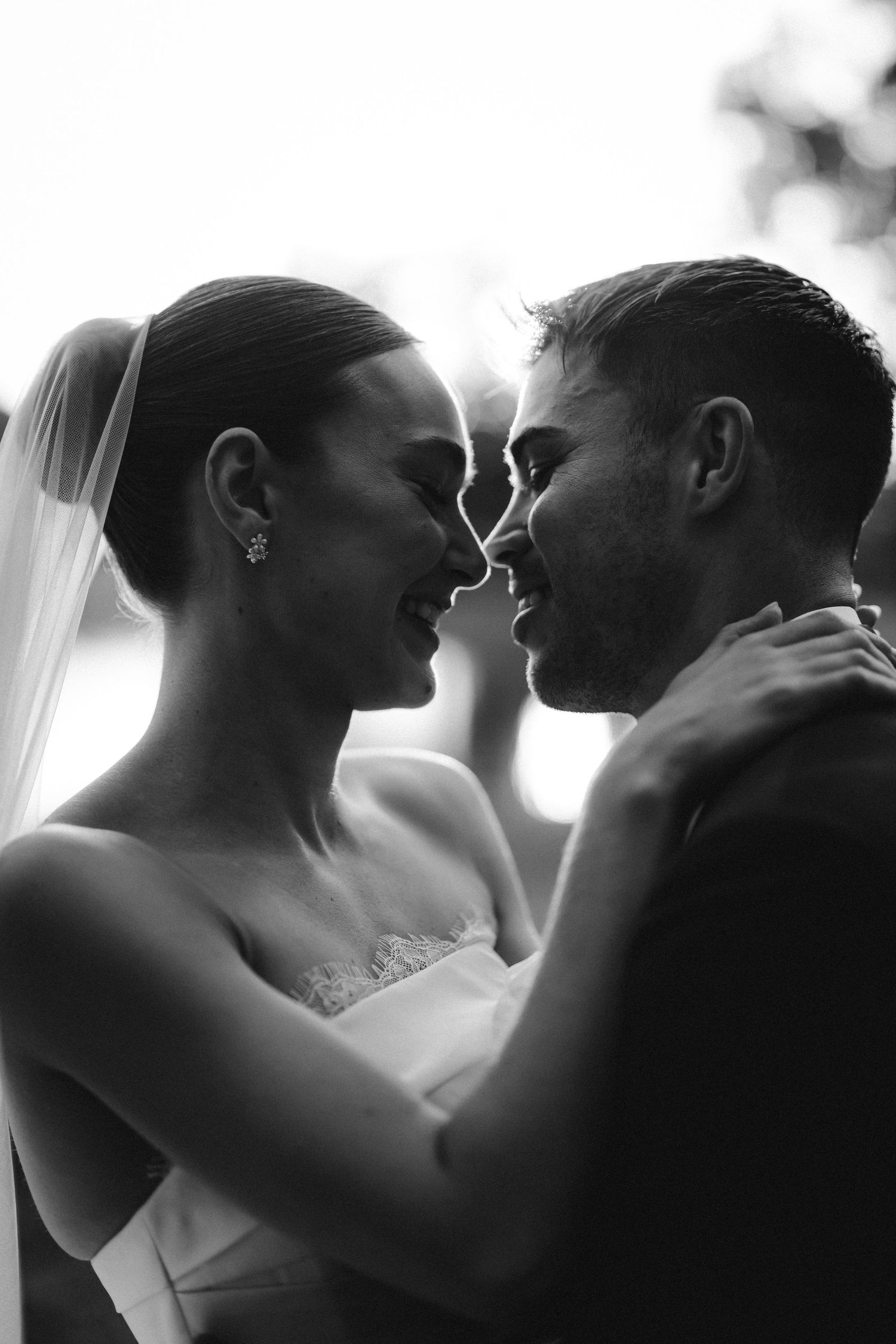 Romantic silhouette of couple in intimate moment against bright background.