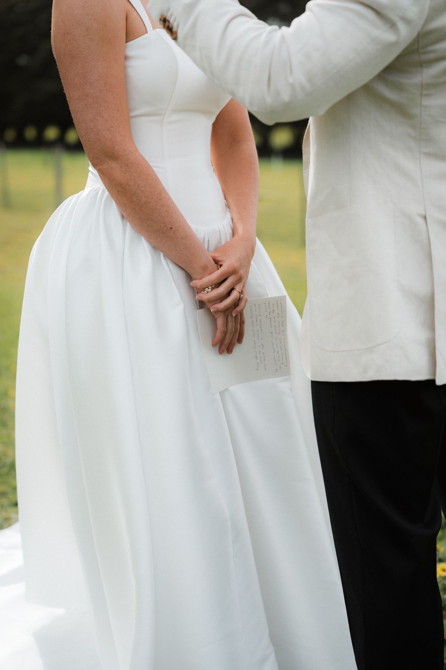Wedding party members in white dresses and formal attire stand together during an outdoor celebration.