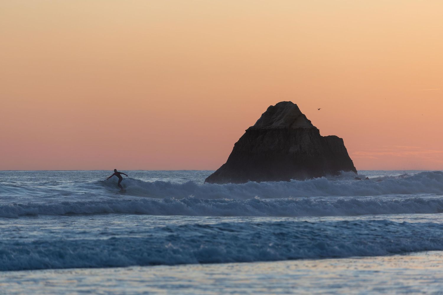 Silhouette of a surfer and rock at sunset in Portimao, Algarve - Anthony West Photography