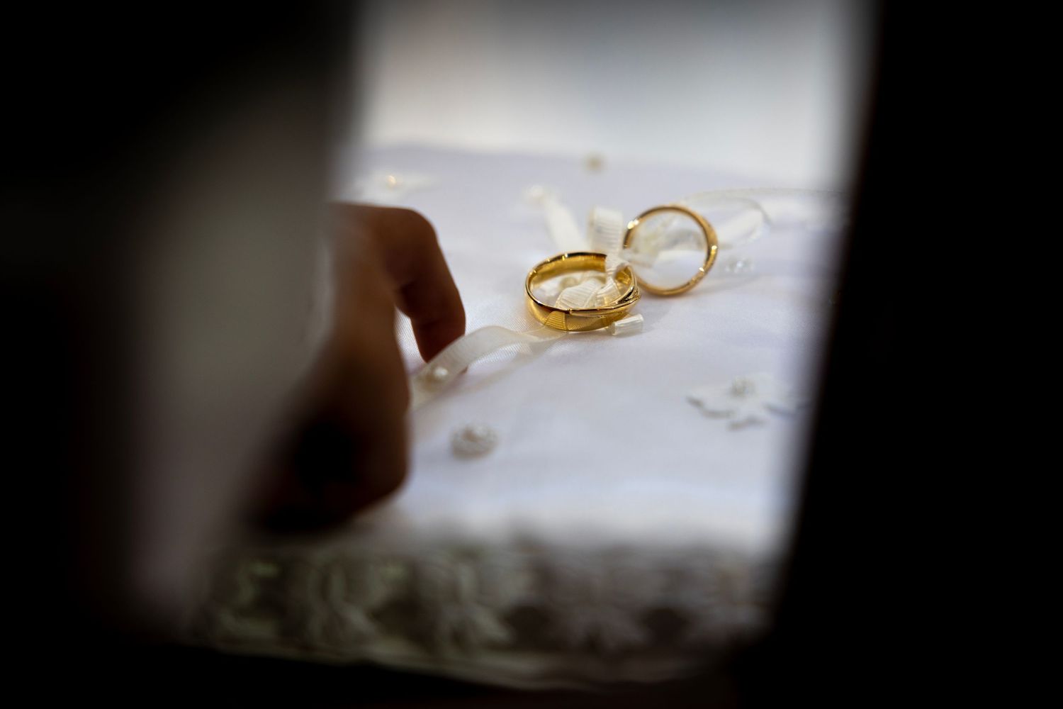 Close-up of gold wedding rings on a cushion held by an altar boy during a church wedding ceremony