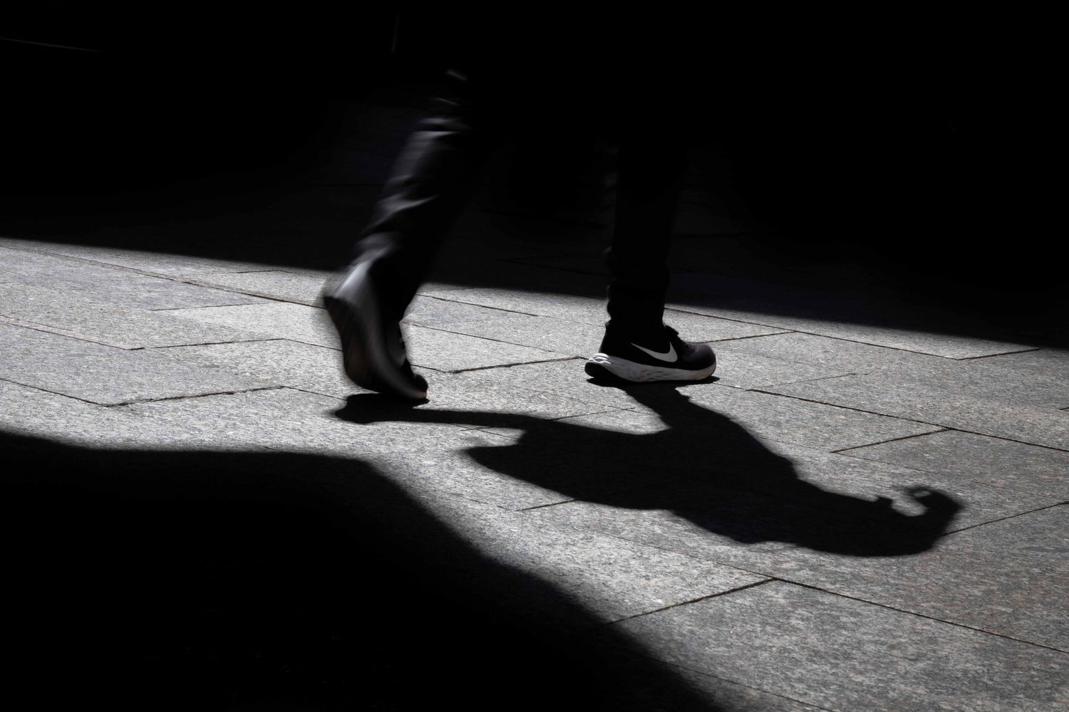 Abstract street photography of legs and shadows on a sunlit pavement in Vigo, Spain, fine art photography by Anthony West