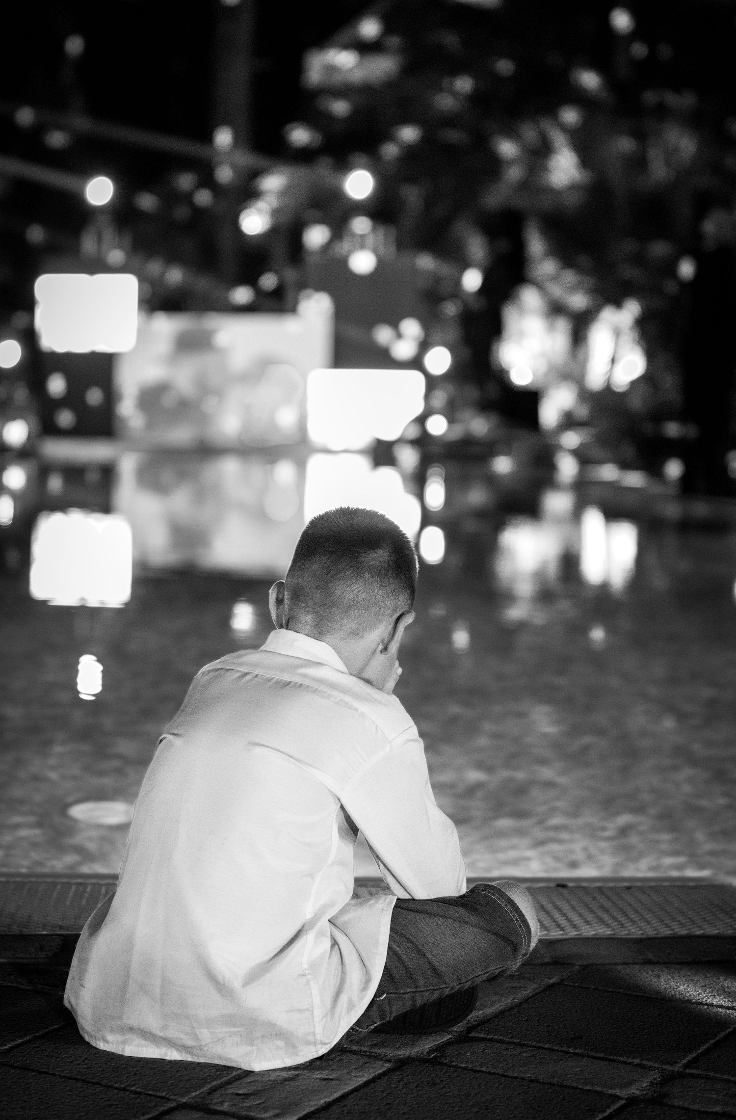 Black and white candid portrait of a young boy sitting by a pool at a wedding, Algarve wedding photography