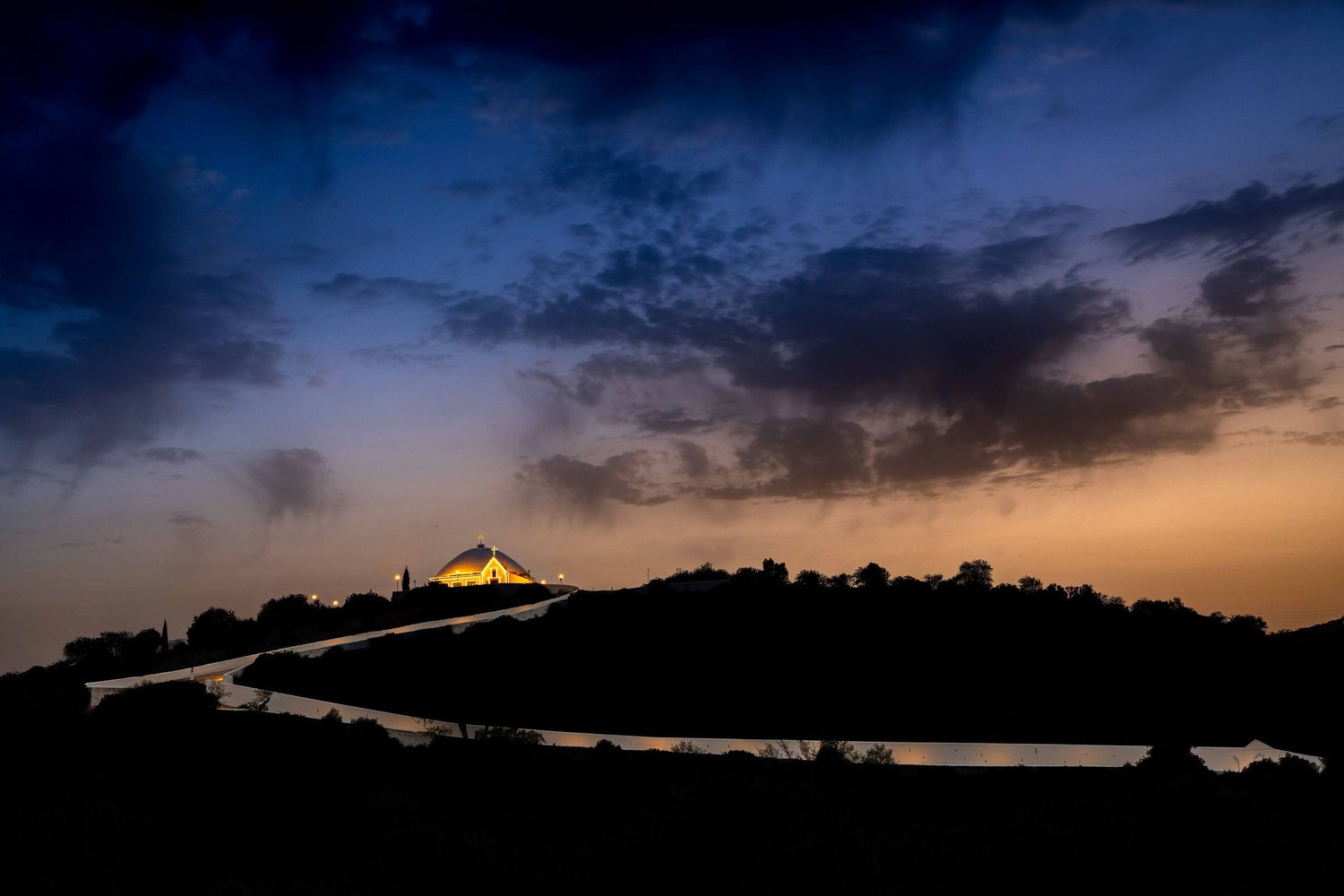 Sunset silhouette of Santuário de Nossa Senhora da Piedade church on a hilltop in Loulé, Algarve, Portugal