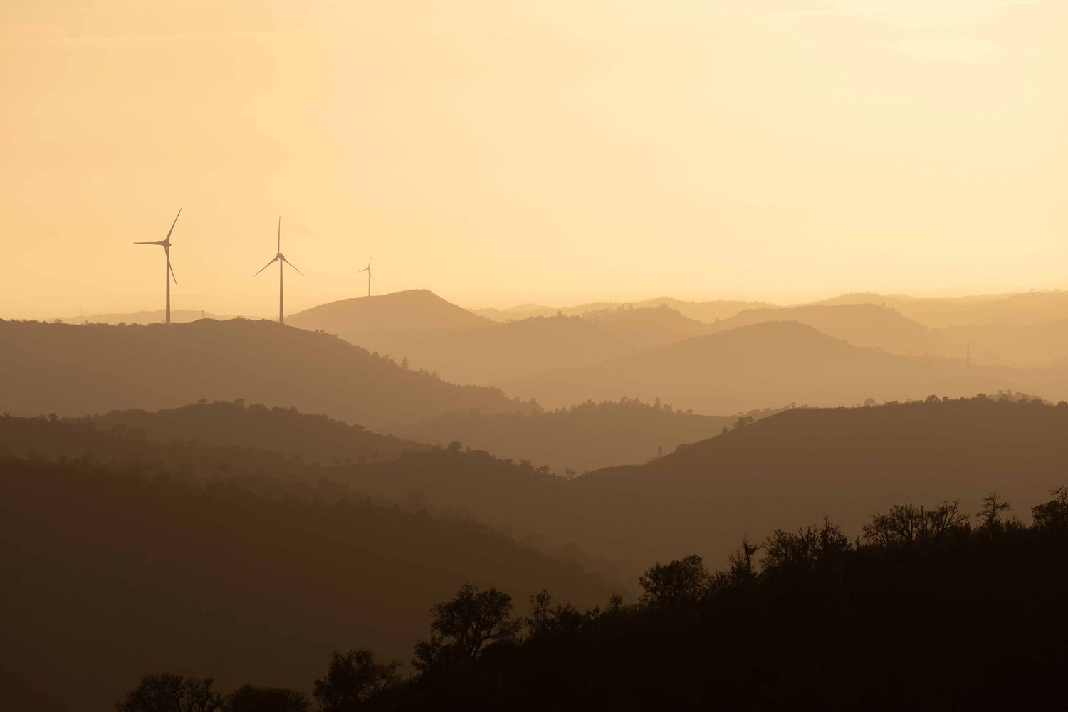 Golden sunset over the Algarve hills with wind turbines in the haze, fine art landscape photography Portugal