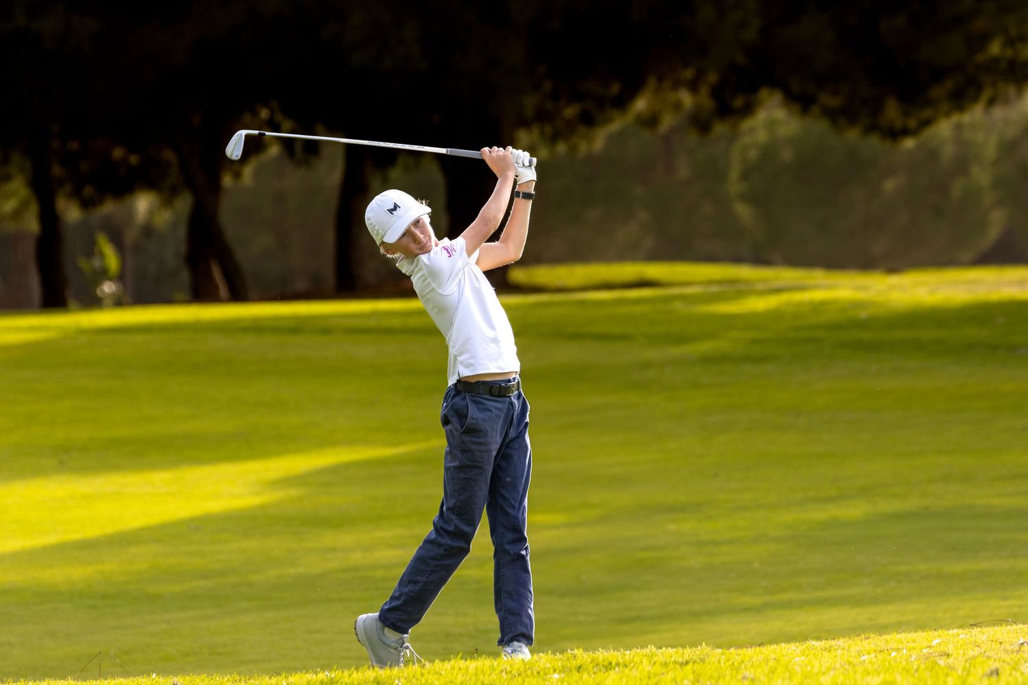 Young golfer playing a iron shot in golden sunlight on an Algarve golf course, Portugal golf photography