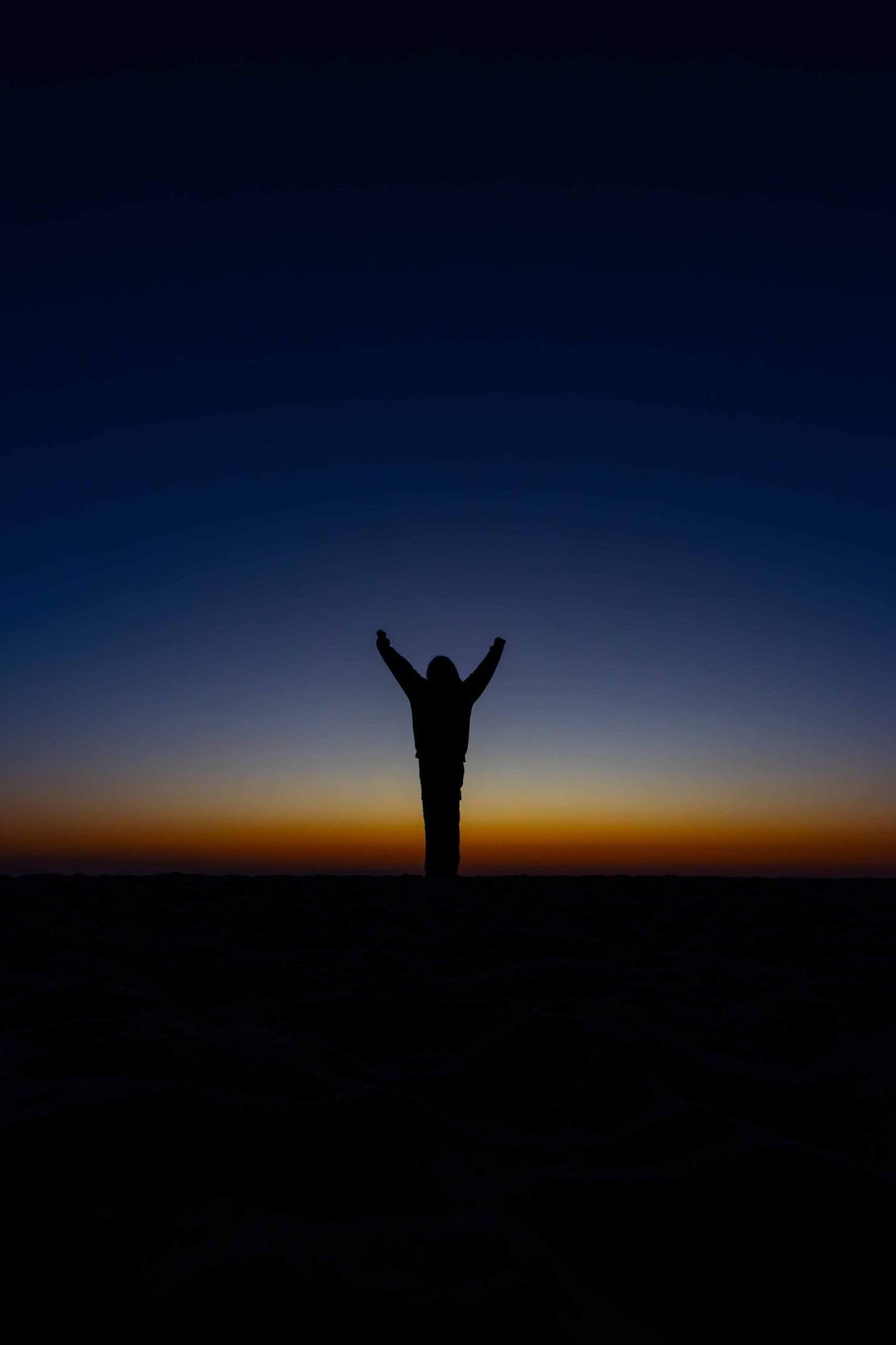 Silhouette of a person with arms raised at sunset on an Algarve beach, fine art photography by Anthony West