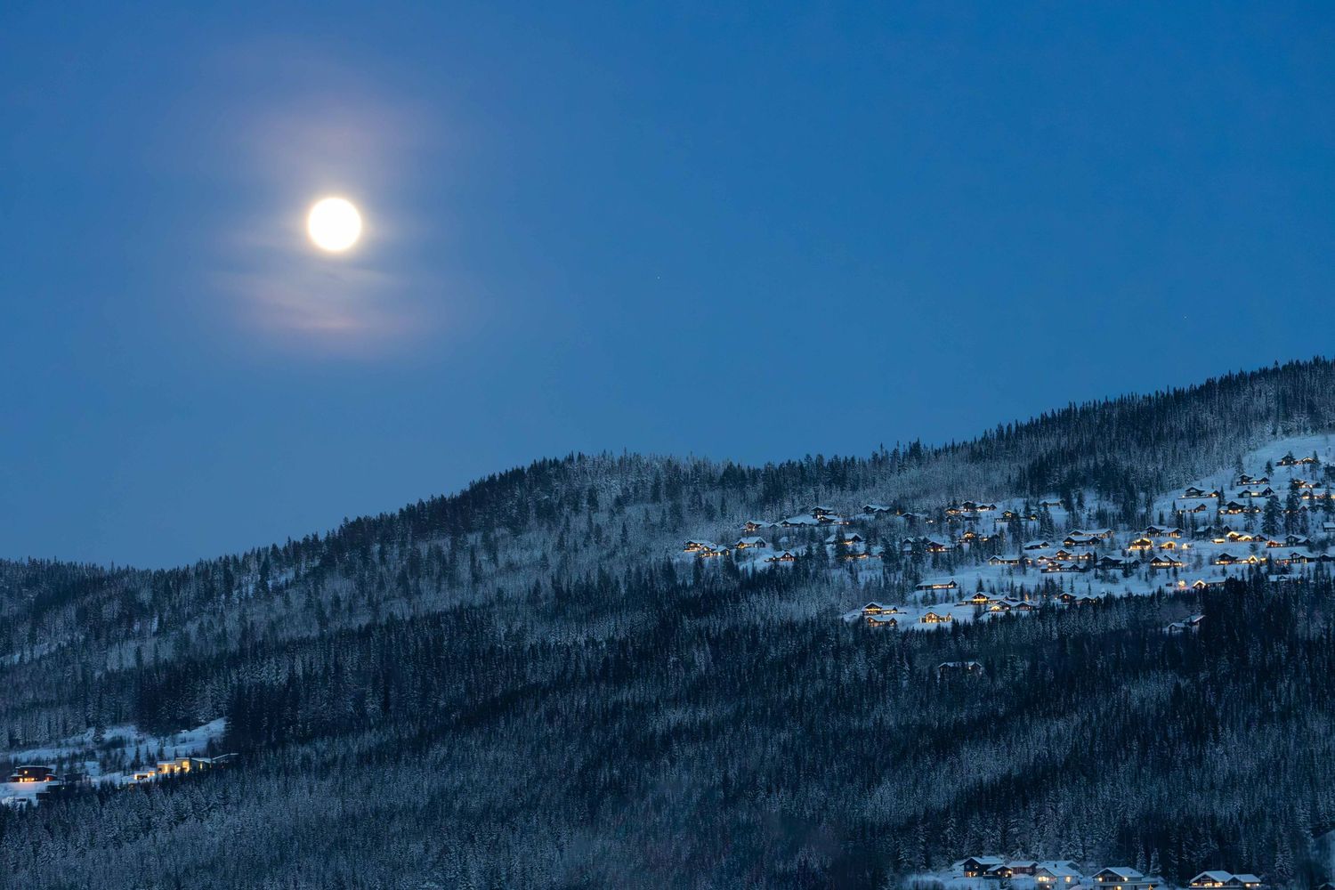 Full moon rising over a snow-covered Norwegian mountain at night, fine art landscape photography