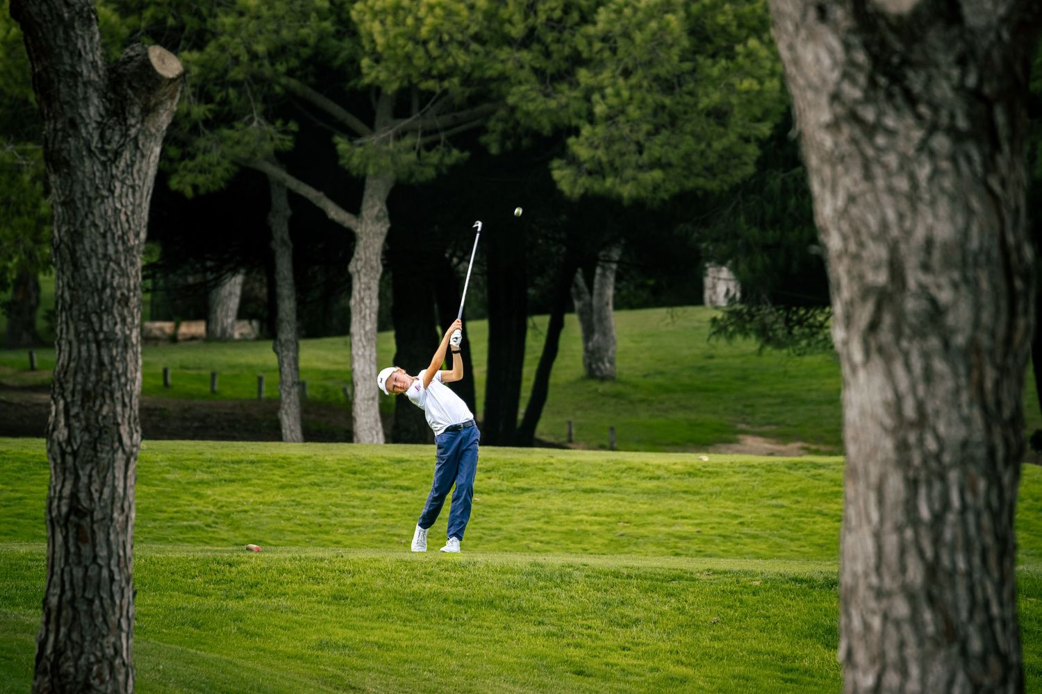 Young golfer teeing off on a tree-lined golf course in the Algarve, Portugal golf action photography