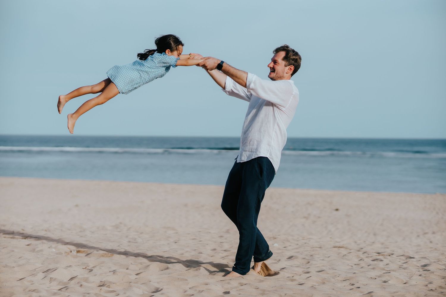 A playful moment captured on the beach with someone being lifted into the air.