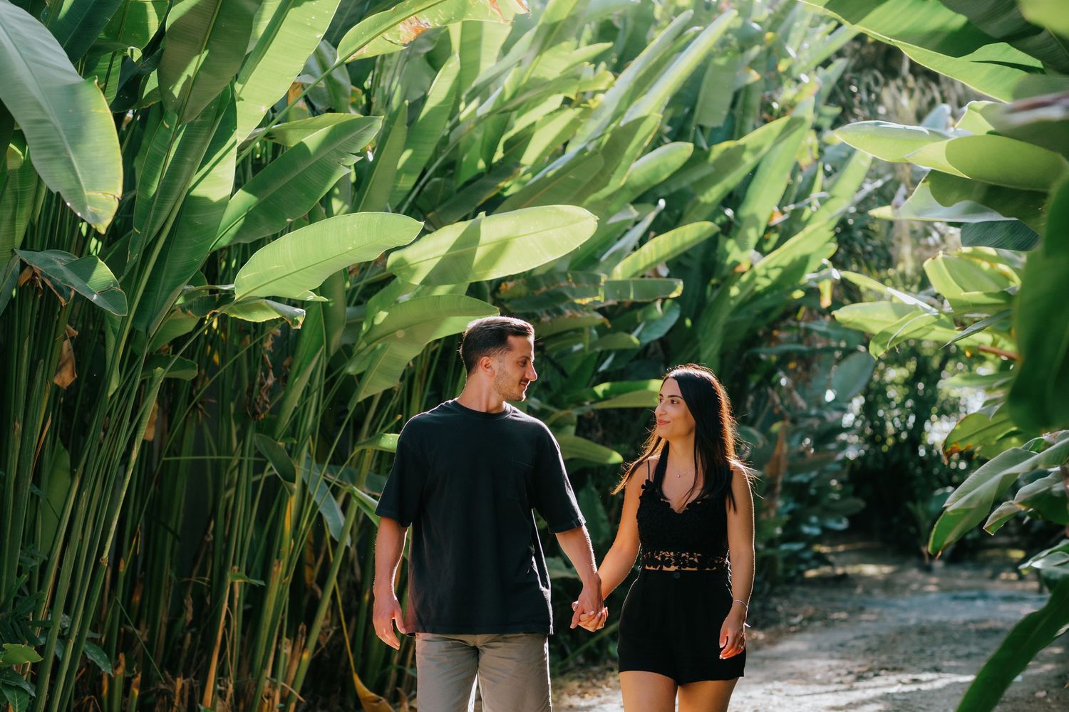A romantic moment between two people surrounded by large tropical leaves.
