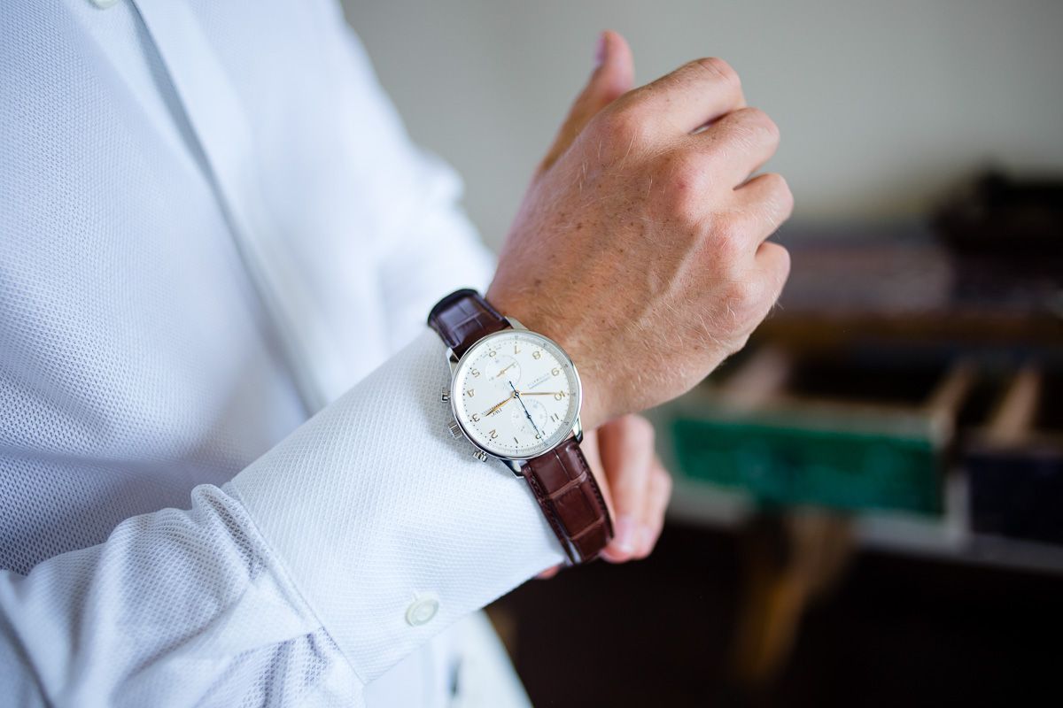 Close-up of elegant watch on groom's wrist with white dress shirt sleeve.