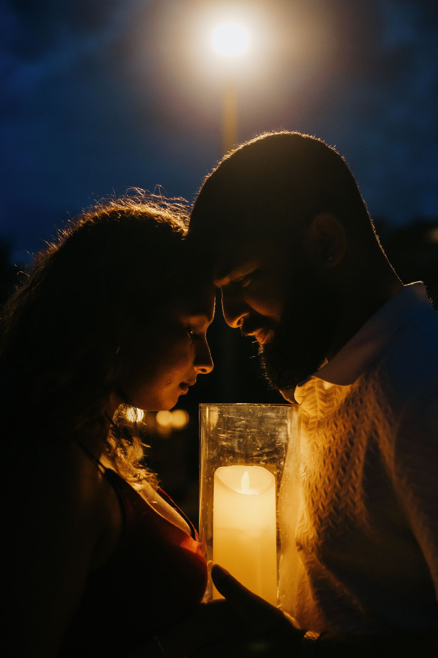 A romantic candlelit moment captured in a series of silhouetted frames against a dark night sky with glowing bokeh lights.