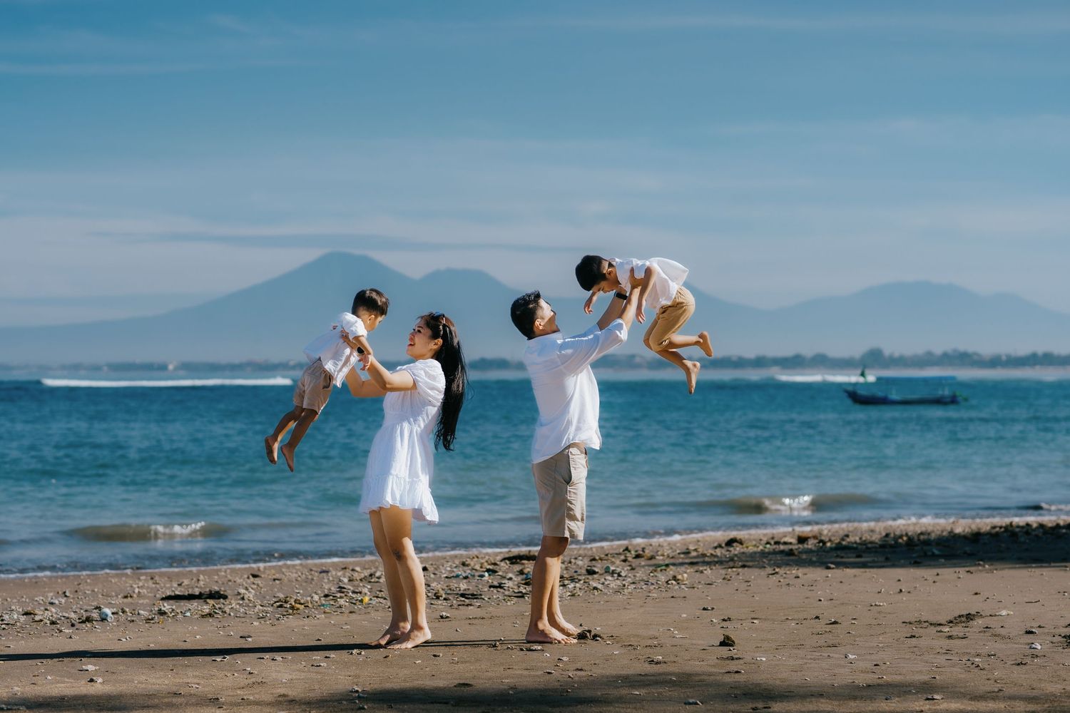 Playful beach photoshoot with ocean and mountains in background.