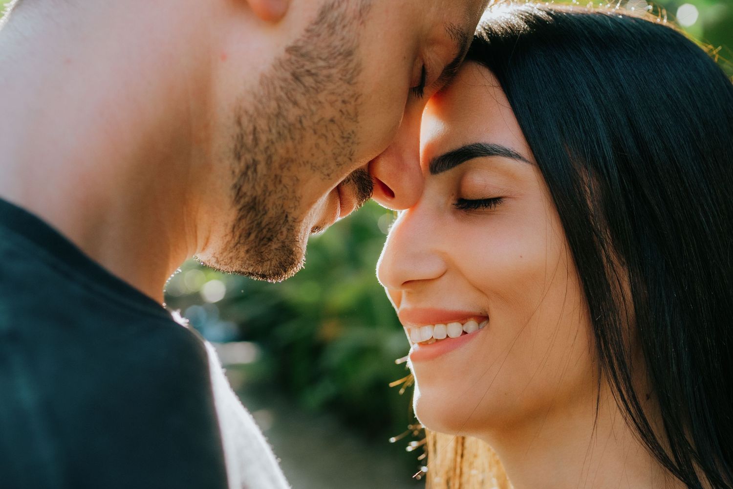 Romantic couple sharing intimate moments in a lush tropical garden setting with green foliage background.