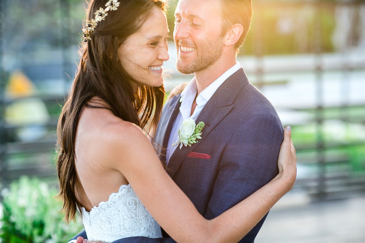 Intimate wedding portrait of couple embracing outdoors in natural sunlight.