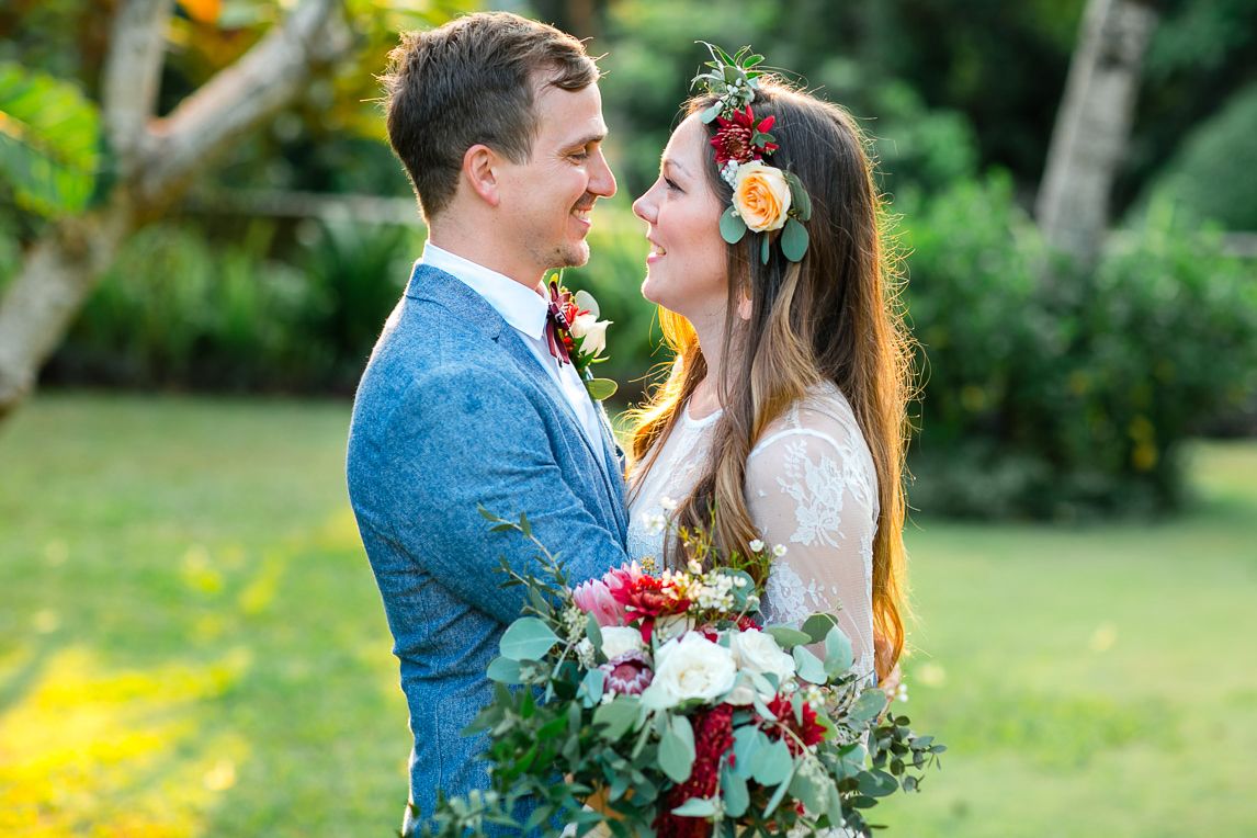A couple shares an intimate moment in a garden setting with colorful floral arrangements.