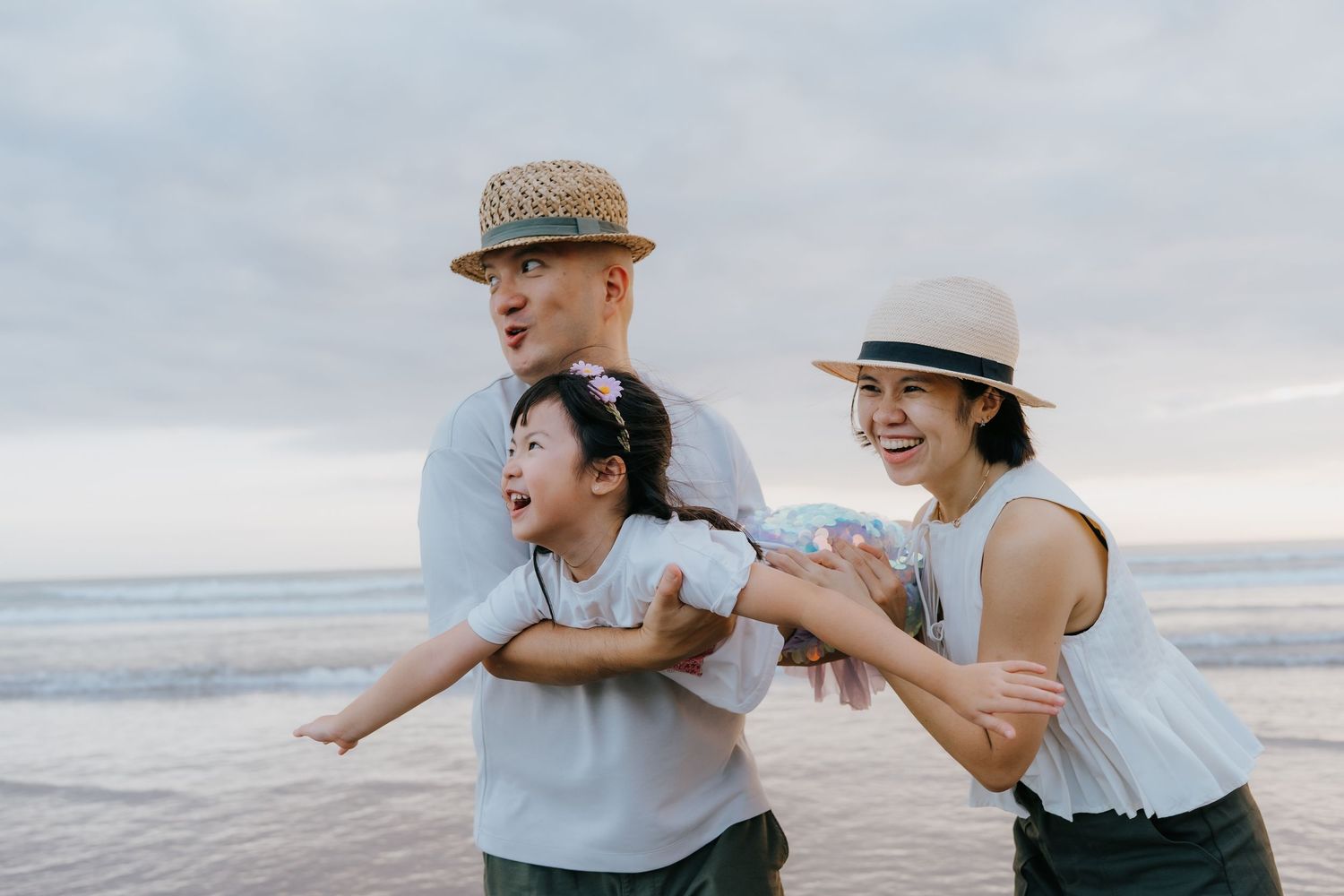 Couple embracing and laughing together on a cloudy beach during a romantic photoshoot session.