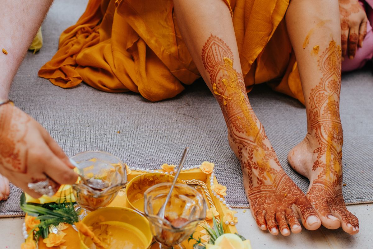 Close-up view of traditional henna designs on feet and hands decorated in intricate patterns.