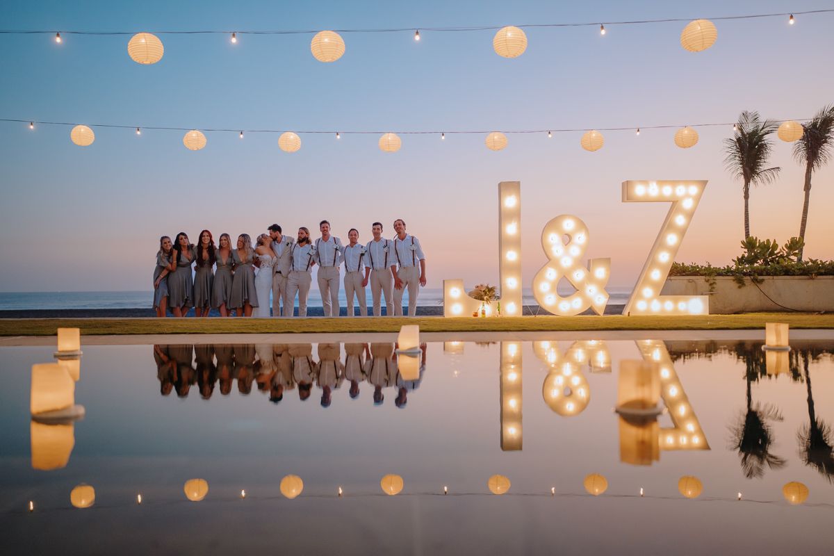 Sunset wedding reception with string lights and illuminated letters creating romantic ambiance.