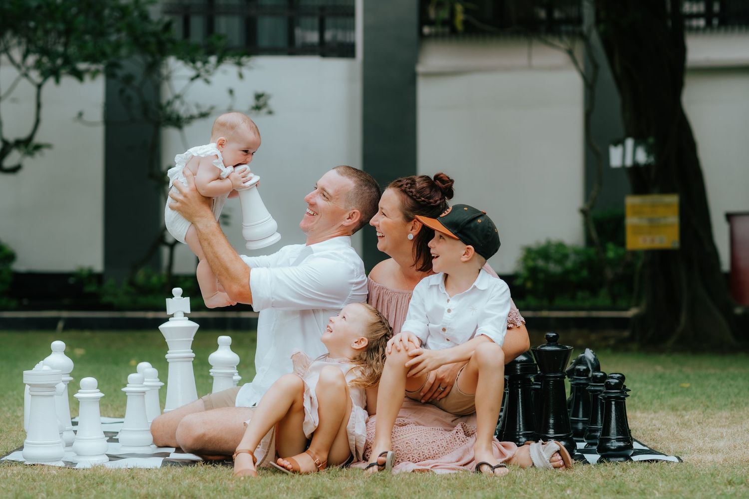 Family having picnic on grass with chess pieces and photography equipment.