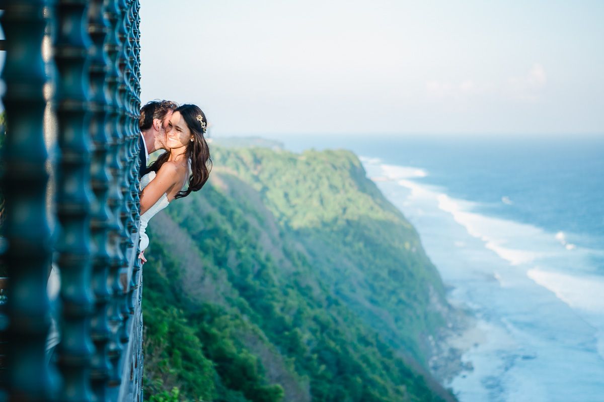 Scenic coastal cliffside view with mountains and ocean waves stretching to the horizon.