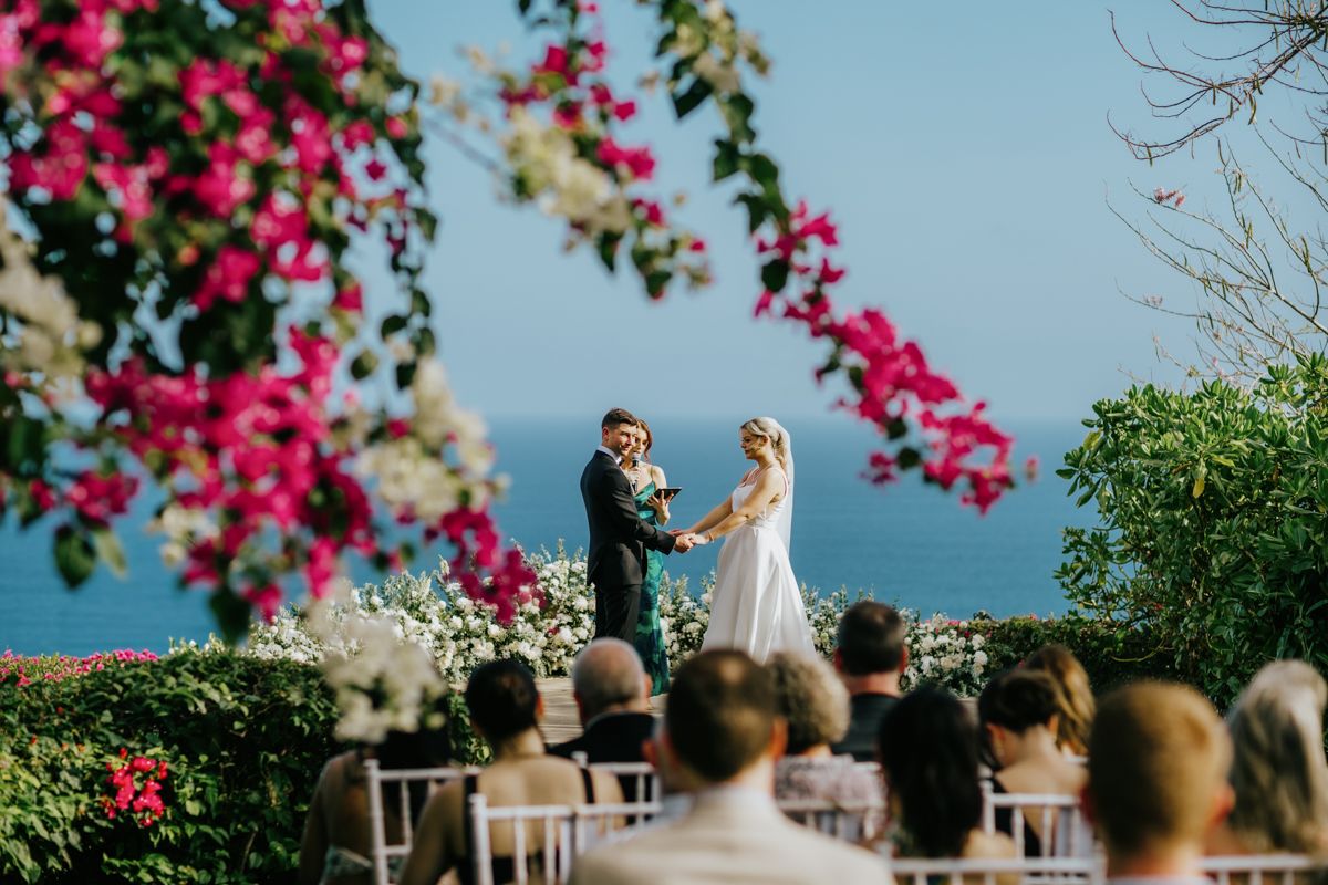 Tropical garden wedding setting with vibrant pink bougainvillea flowers framing the ceremony.