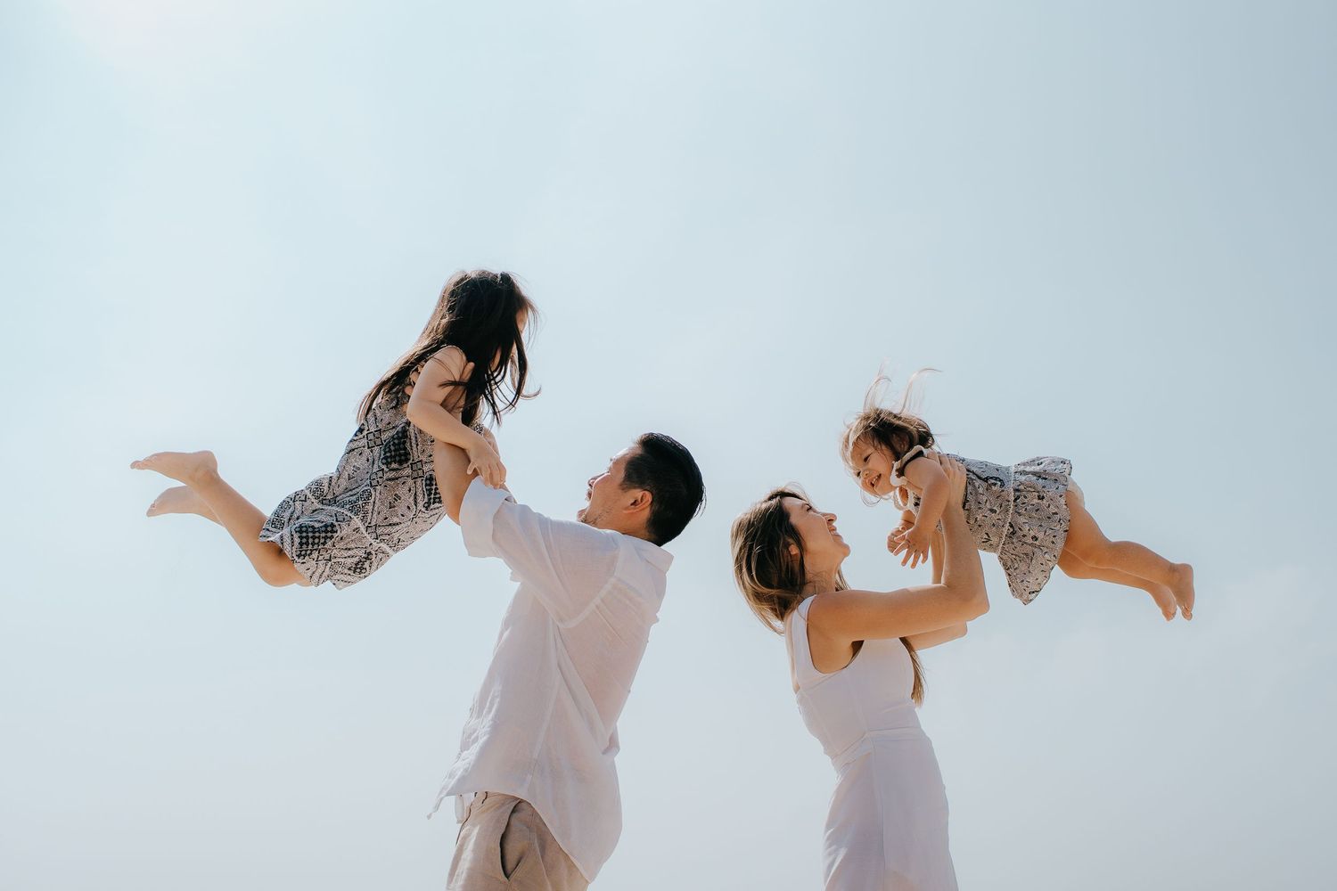 Dancers in white outfits performing contemporary dance moves against a light background.
