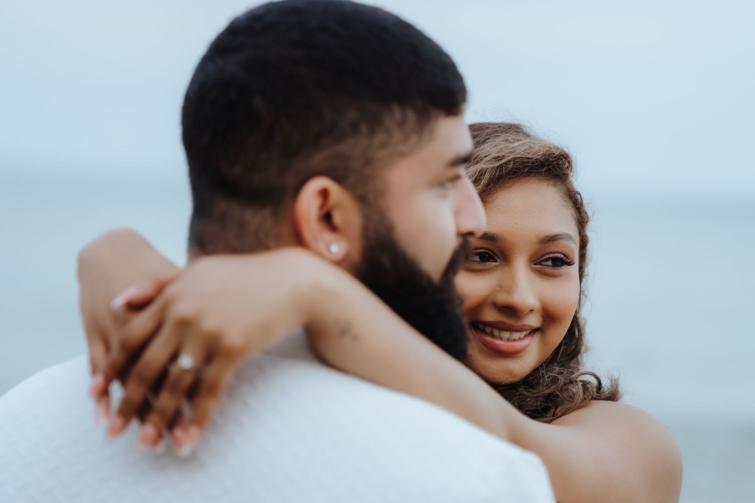 Intimate close-up shot of a couple embracing and smiling during an outdoor photoshoot.