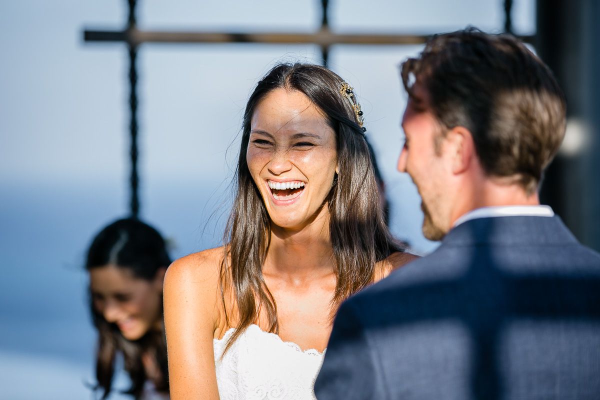 Joyful wedding moment captured during outdoor ceremony with ocean backdrop.