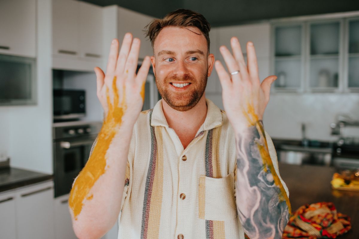 Person in white shirt showing hands to camera with joyful expression in indoor setting.