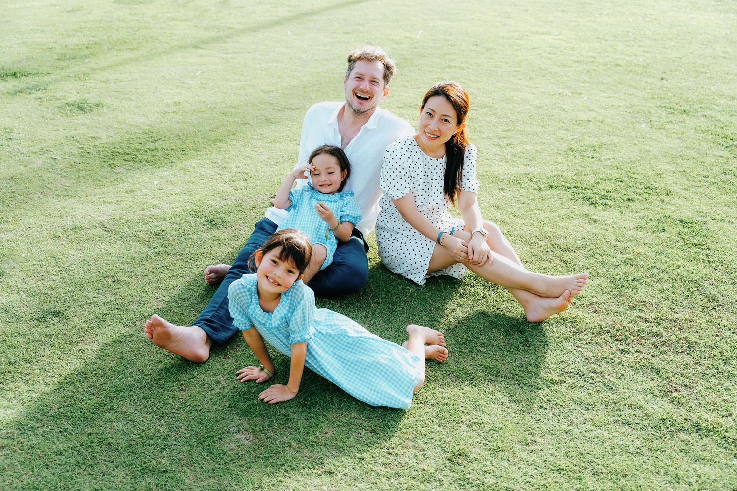 Happy family relaxing and playing together on green grass outdoors.
