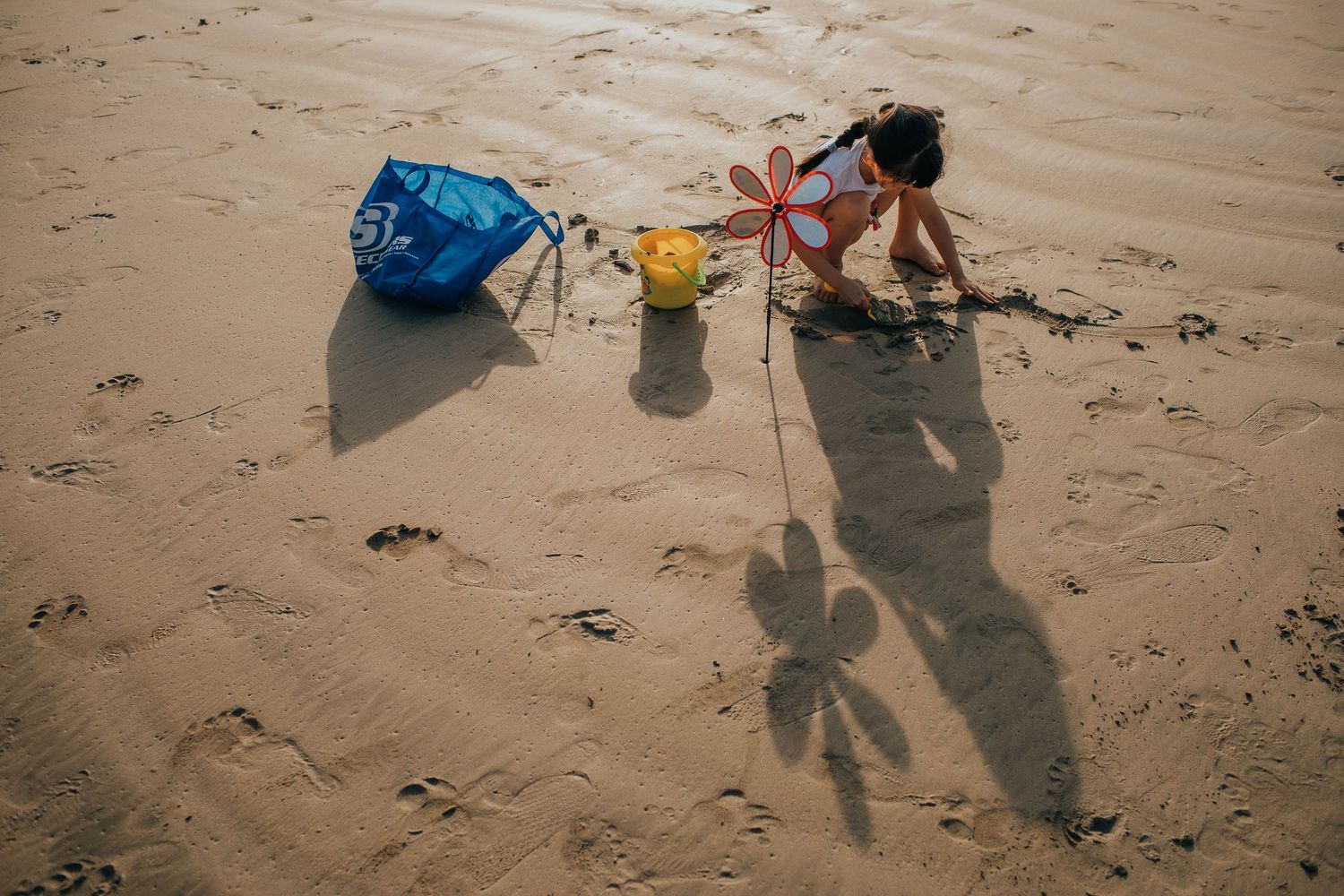 Children playing with colorful pinwheels and toys on a sandy beach.