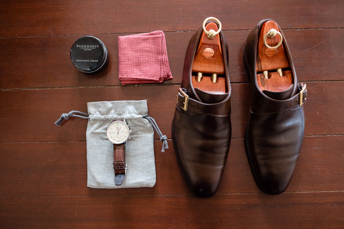 Wedding accessories including rings, shoes, and accessories arranged on wooden surface.