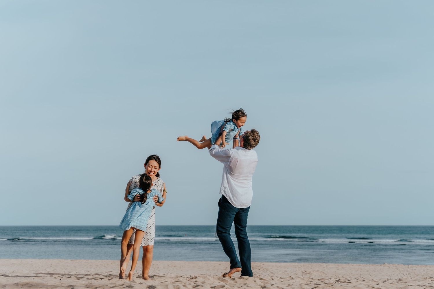 A playful beach scene with people enjoying themselves against an ocean backdrop.