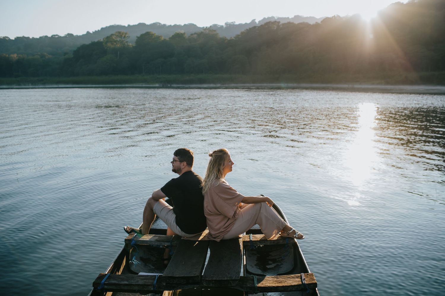 Couple relaxing together on dock overlooking serene lake at sunset.
