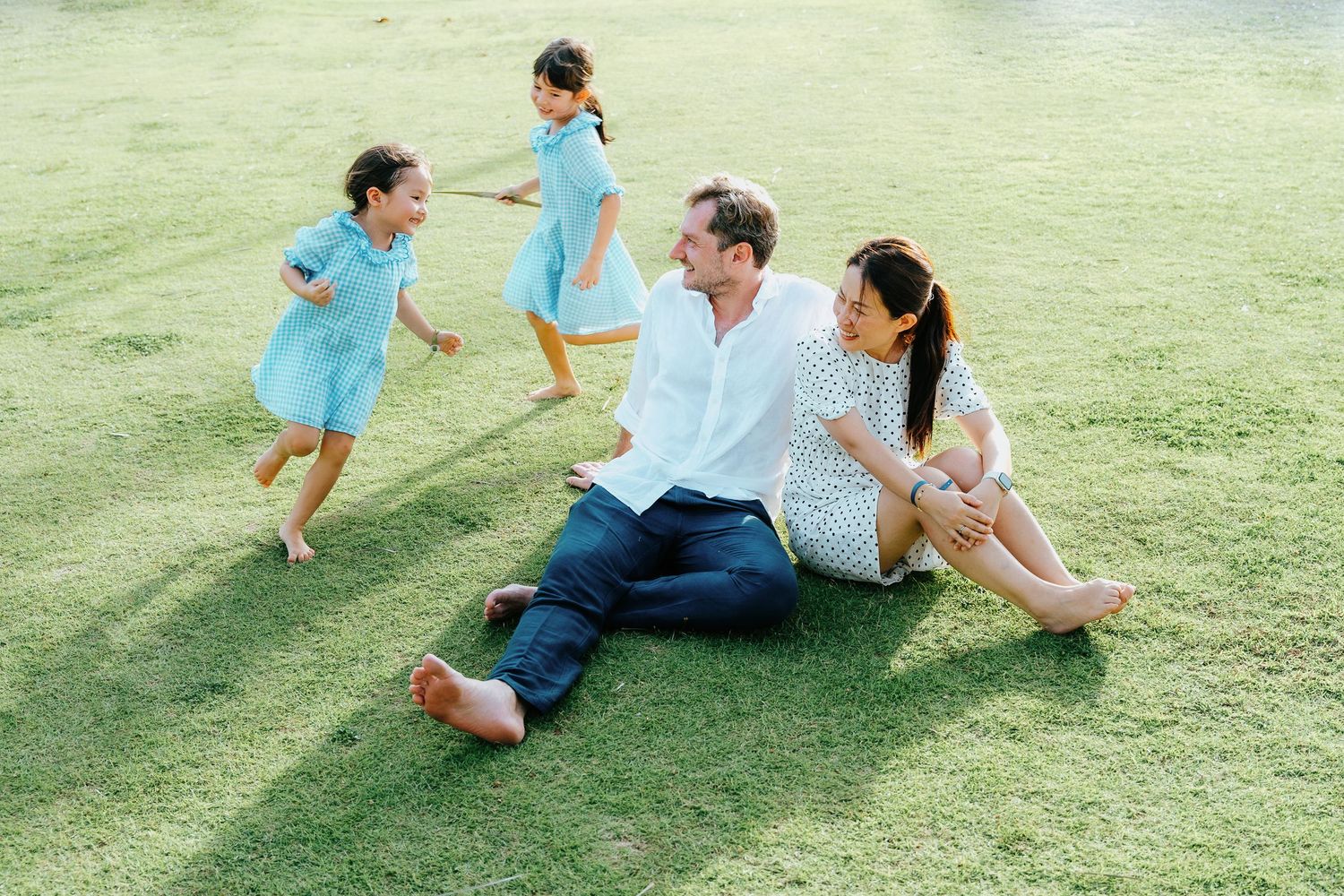 A joyful outdoor scene with people relaxing on lush green grass wearing light blue outfits.