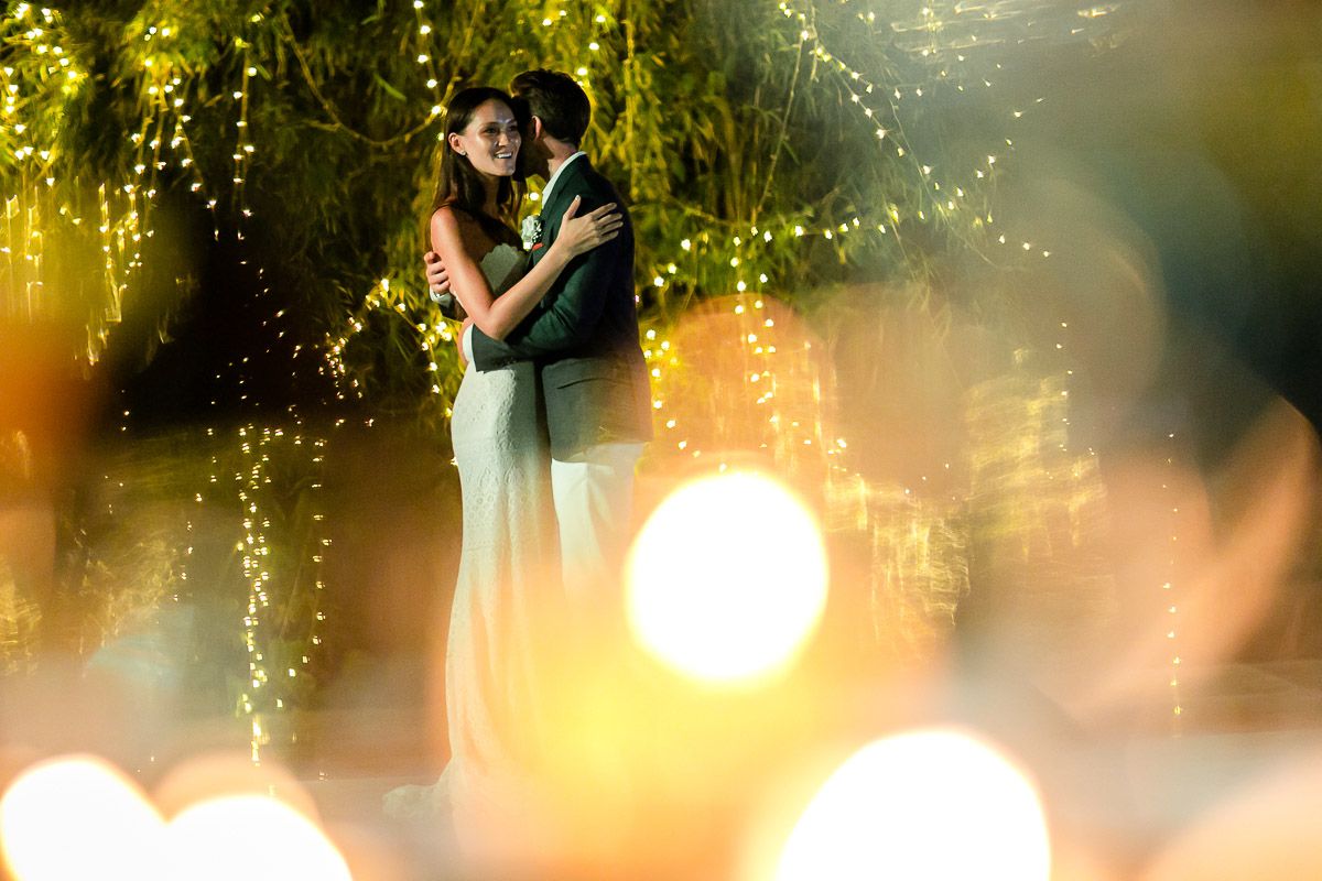 Wedding reception guests enjoy an outdoor evening celebration with glowing string lights creating a magical atmosphere.