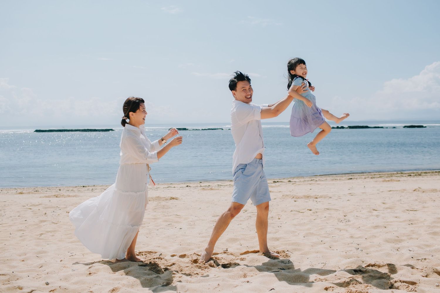 Playful beach photoshoot with waves and shoreline in the background.