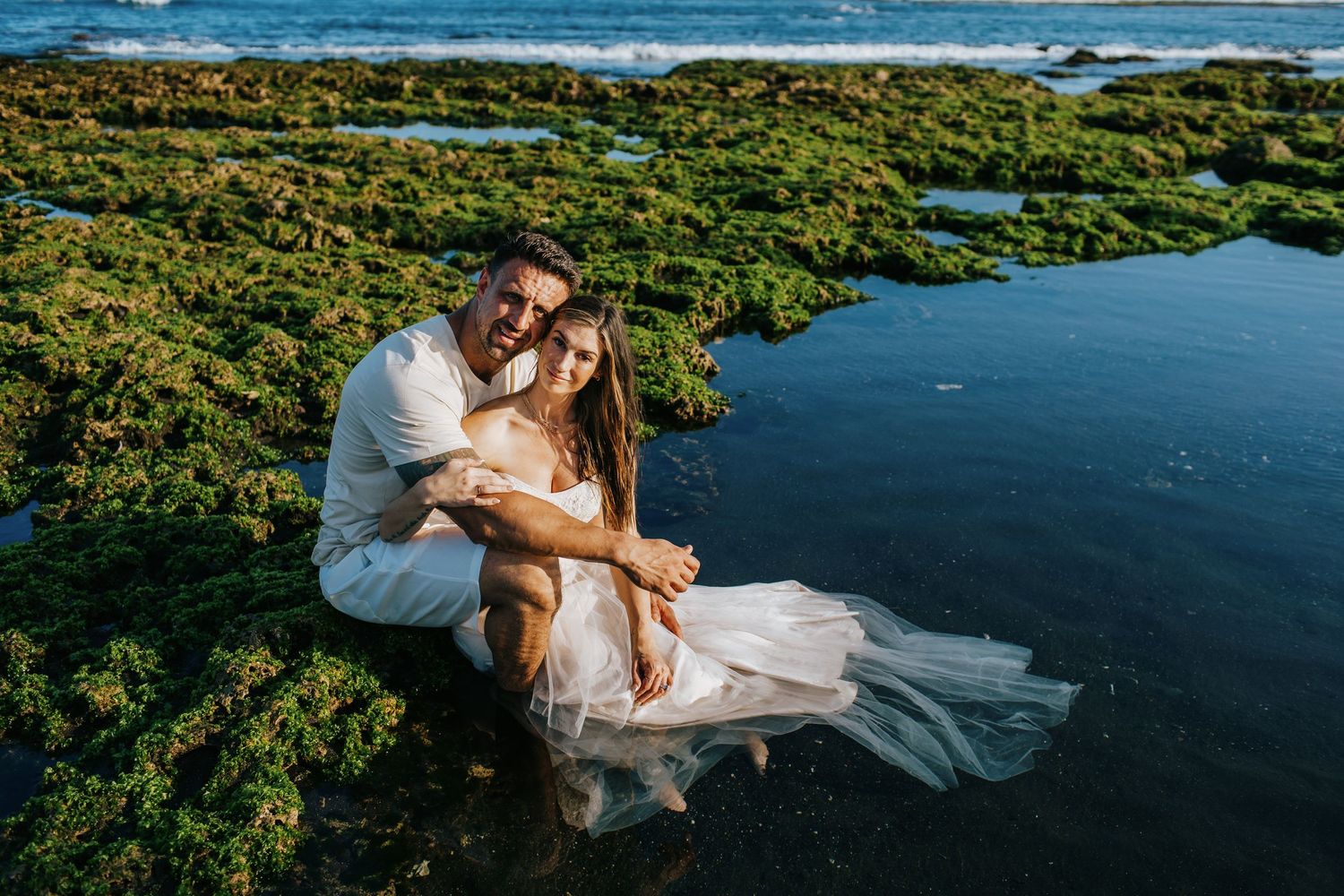 Aerial drone photos of a couple in formal attire posing on a wooden dock surrounded by tropical waters and greenery.