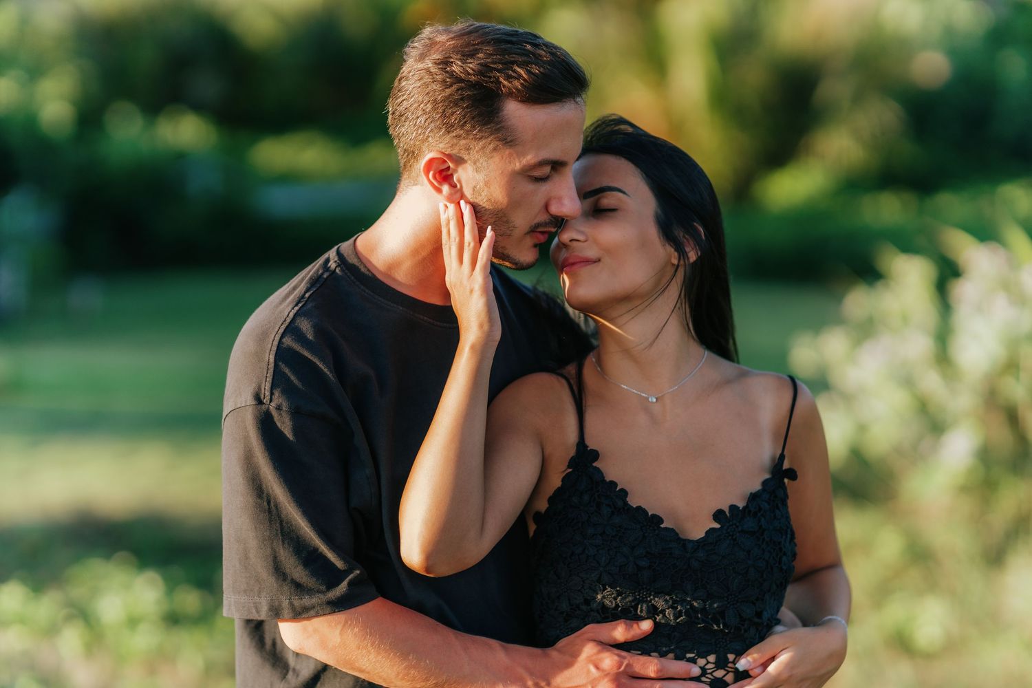 Couple embracing in a lush garden setting with soft natural lighting.