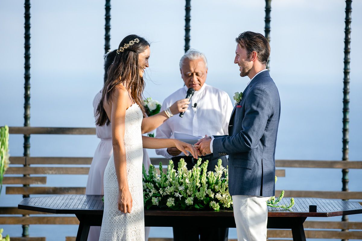 Outdoor wedding ceremony with officiant and couple exchanging vows by the ocean.
