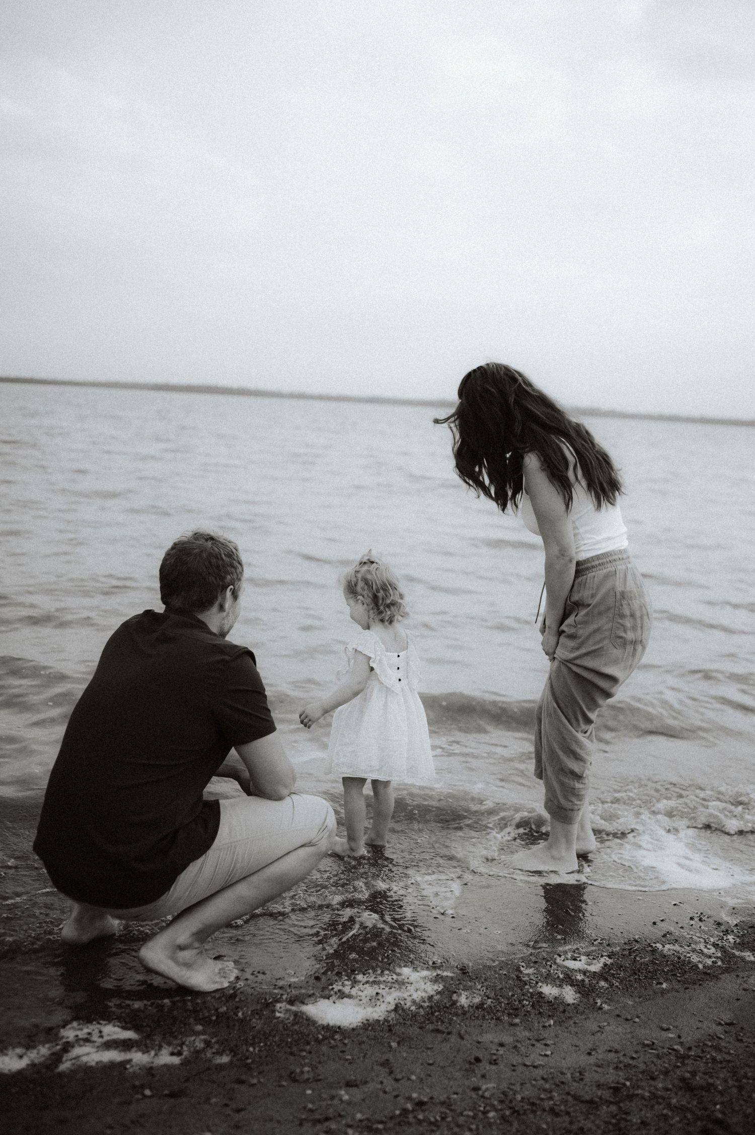 A sequence of black and white photos shows a family playing and splashing at the beach shoreline.